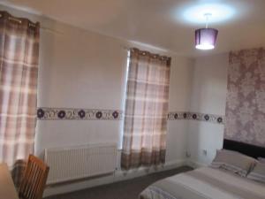 a bedroom with a bed and two windows with curtains at Villa Parrin in Manchester
