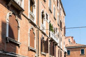 ein rotes Backsteingebäude mit Fenstern und einem Balkon in der Unterkunft San Zaccaria Apartment in Venedig