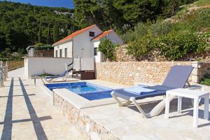 a villa with a swimming pool and two chairs and a house at Holiday home Nina in Bol