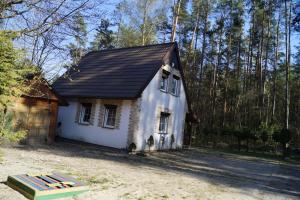 una pequeña casa blanca con techo negro en Uroczy domek do wynajęcia w Bogaczewie nad jeziorem Narie, en Morąg