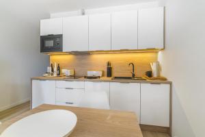 a kitchen with white cabinets and a sink at eMeN Apartamenty Jastarnia in Jastarnia