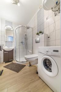 uma casa de banho com um chuveiro e uma máquina de lavar roupa em eMeN Apartamenty Jastarnia em Jastarnia