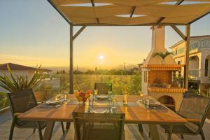 a wooden table and chairs on a patio with a fireplace at Vista Blu Villa in Vlachata
