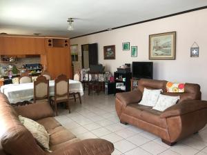 sala de estar con sofás de cuero y comedor en Casa del Suizo, en Alajuela