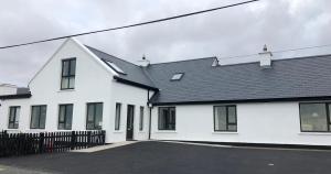 a white house with a black roof at Teach Cruachan Bed and Breakfast in Dooagh