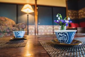 dos tazas y platillos azules y blancos sobre una mesa de madera en Guest House Yonemuraya en Matsue