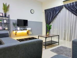 a living room with a couch and a table and a tv at Puchong Setiawalk 8-12 pax 5min LRT Cozy Apartment in Puchong