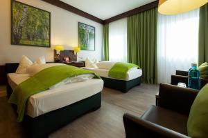 Habitación de hotel con 2 camas con sábanas verdes en Hotel Goldener Hirsch, en Bayreuth