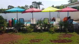eine Gruppe von Sonnenschirmen und Stühlen neben einem Pool in der Unterkunft Villa de Colores 3 Rooms 5 king Beds in Sosúa
