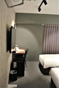 a bedroom with a desk and a bed and a bed and a desk at Doudian DDiNN Hotel in Taichung