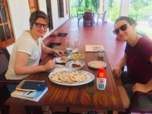 two women sitting at a wooden table with food at Punkalasa tourist lodge in Anuradhapura +29 photos