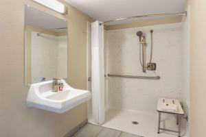 a white bathroom with a sink and a shower at Days Inn Merced / Yosemite Area in Merced