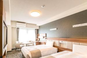 a hotel room with two beds and a table at Comfort Hotel Shin-Osaka in Osaka