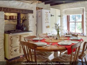 a kitchen with a wooden table with a red table cloth at Y Teras in Clynderwen
