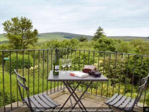 a table with two chairs and a bottle of wine on a balcony at Y Teras in Clynderwen