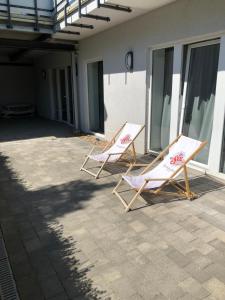 2 sillas de jardín sentadas en un patio junto a un edificio en Modernes Appartement en Gladbeck