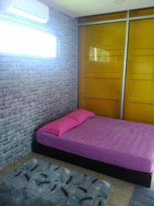 een slaapkamer met een paars bed en een bakstenen muur bij Yellow Cube at Lumut Cube Homestay Kontena in Lumut