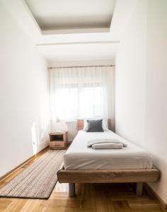 ein weißes Schlafzimmer mit einem Bett und einem Fenster in der Unterkunft Premium 1 apartments in Aranđelovac