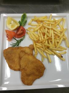 un plato blanco con papas fritas y un trozo de pescado con patatas fritas en Residence Terentis, en Terento