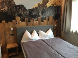 łóżko z białymi poduszkami w pokoju z obrazem w obiekcie Ski Holidays Apartments w Livigno