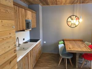a kitchen with a table and a clock on the wall at Ski Holidays Apartments in Livigno