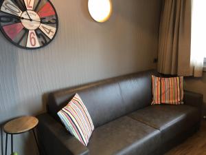 a leather couch in a room with a clock on the wall at Ski Holidays Apartments in Livigno
