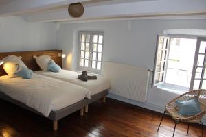 a bedroom with a bed and a chair and windows at Gîte le pied du géant - Local sécurisé pour les vélos in Tournon-sur-Rhône