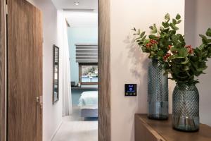 a hallway with two vases with flowers on a dresser at Ciel Collection Suites in Chania