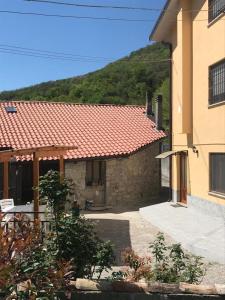 ein Haus mit rotem Kacheldach und einem Gebäude in der Unterkunft Alloggio da Massimo in San Leonardo
