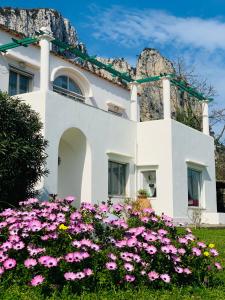 un bâtiment blanc avec des fleurs roses devant lui dans l'établissement Marunnella Suites, à Capri