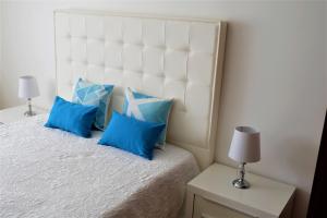 a bedroom with a white bed with blue pillows at Estrelinha GuestHouse in Nazaré