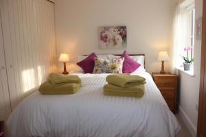 Un dormitorio con una cama blanca con toallas. en Mistletoe Cottage, en York