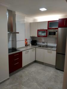 een keuken met rode en witte kasten en apparaten bij Bonito apartamento in Torre del Mar