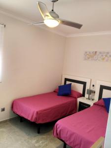 twee bedden in een kamer met roze lakens bij Bonito apartamento in Torre del Mar