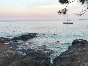 a person swimming in the ocean with a sail boat at T2 Moderne avec jardin in Rayol-Canadel-sur-Mer