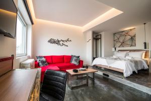 een woonkamer met een rode bank en een bed bij AthinA STREETAPARTMENTS in Athene