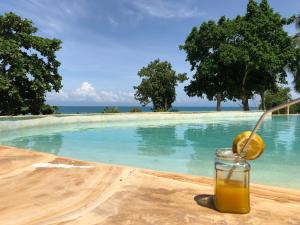 a glass of orange juice next to a swimming pool at Mangrove Lodge in Zanzibar City