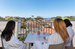 three girls sitting at a table with wine glasses at Hotel Residence Villa Marzia in Marina di Pietrasanta