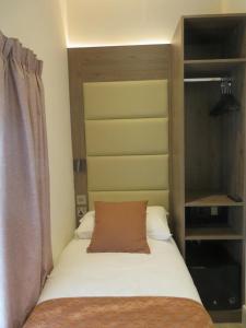 a bed with a brown pillow on top of it at Glendale Hyde Park Hotel in London