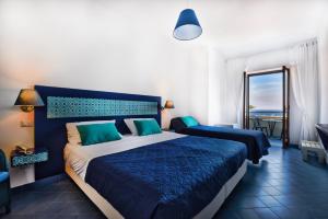 a bedroom with a blue and white bed and a balcony at Hotel Baia Di Puolo in Massa Lubrense