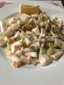 a white plate of shrimp with a lemon wedge at Hostal Restaurante Taibilla in Nerpio