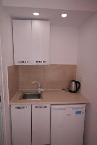 a kitchen with white cabinets and a sink at Alexandros Studios in Asprovalta