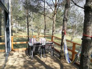 Kamień的住宿－Glass Cottage in Jelenska Huta with terrace，树木繁茂的甲板上的桌椅
