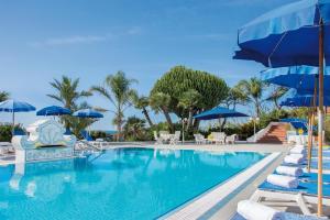 a swimming pool with chairs and umbrellas at Hotel Capizzo in Ischia