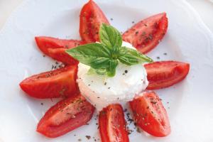 a plate of strawberries with ice cream and a green garnishment at Hotel Capizzo in Ischia