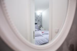 
a white bed sitting in a bedroom next to a mirror at Sunny Nest Apartments in Kotor
