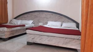 twee bedden in een slaapkamer met een groot hoofdeinde bij The Wayside Inn in Matheran