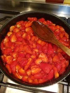 a pan filled with strawberries and a wooden spoon at La Terrasse de Peyre in Comprégnac