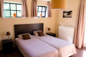een slaapkamer met een bed met witte lakens en ramen bij Bed and Breakfast De Grote Byvanck in Westervoort