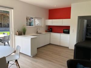 een keuken met witte kasten en een rode muur bij Ô Spa Ren in Spa